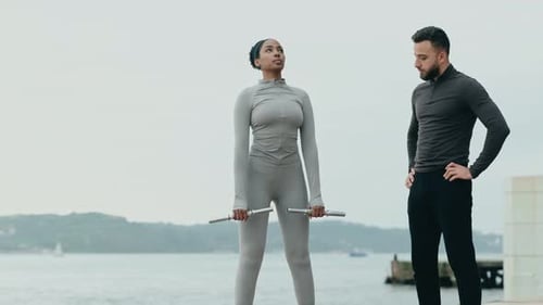 Woman Lifting Weights with Trainer on Waterfront
