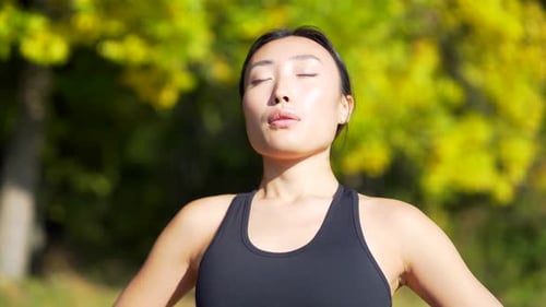Close up portrait young happy asian woman standing in nature between forest trees relaxes, breathes