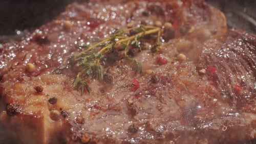 Fresh Marbled Beef with Pepper Salt and Rosemary Closeup Macro Cooking Juicy Steak on Grill with Oil