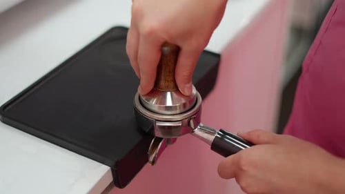 Person Tamping Coffee in Portafilter at Workplace