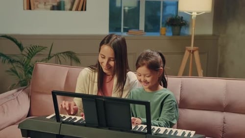 Woman and Child Play Piano Together at Home