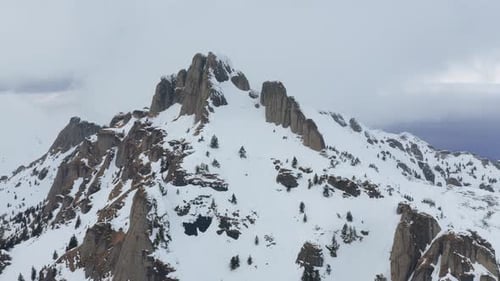 Sommet accidenté des montagnes de Ciucas recouvert de neige sous un ciel couvert, paysage hivernal