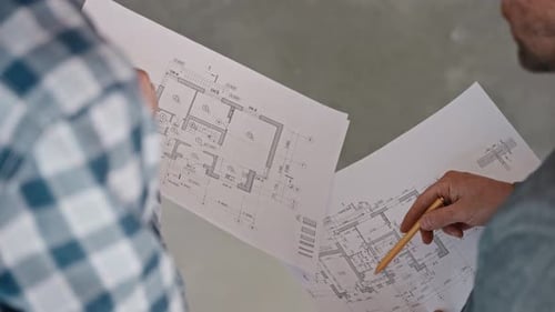 Un ingénieur et un constructeur discutent d'un projet de maison sur la base de dessins détaillés des travaux de construction