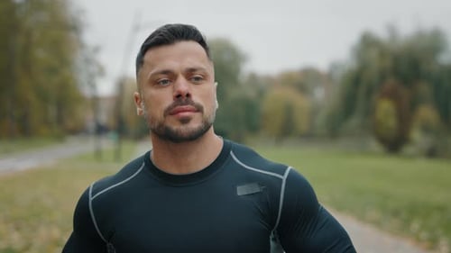 Attractive Athletic Man Jogging Through the Park A Man in Slowmotion Running As Part of His Fitness