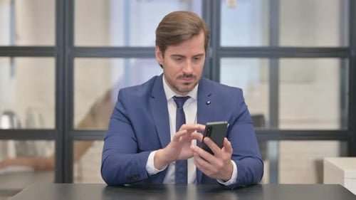 Businessman Using Mobile Phone at Office Desk