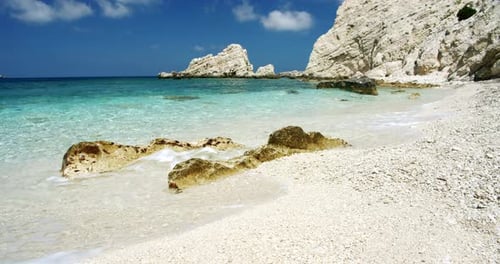 Clear Sea Waves Splashing on Peaceful White Beach with Pebbles Seascape with Rocks in Background