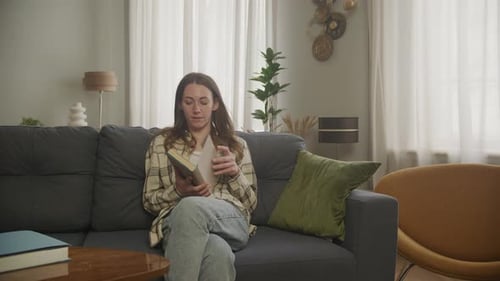 Woman Reading Book on Gray Sofa at Home