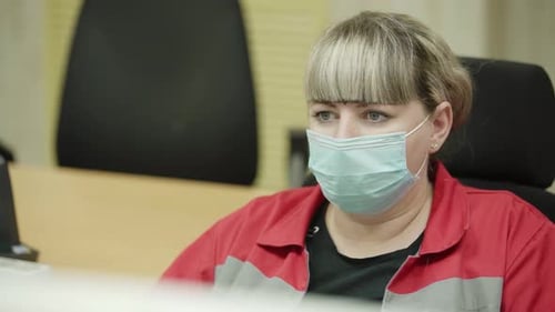 A Woman is Diligently Working in an Office Environment While Wearing a Protective Mask Stock Clip