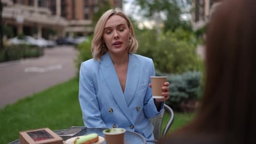 Women Enjoying Coffee and Pastries Outdoors in City