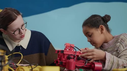 Little Biracial Girl Studying Robotics with Help of Young Female Teacher
