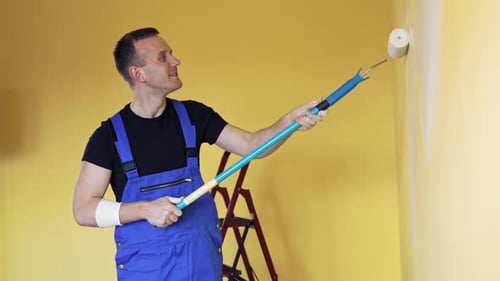 Young man doing renovation. Portrait of a painter worker doing makeover in the room.