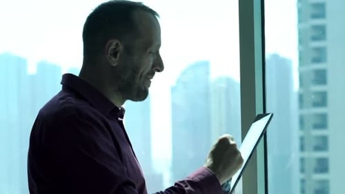Happy businessman celebrates investment success reading good news on tablet in office