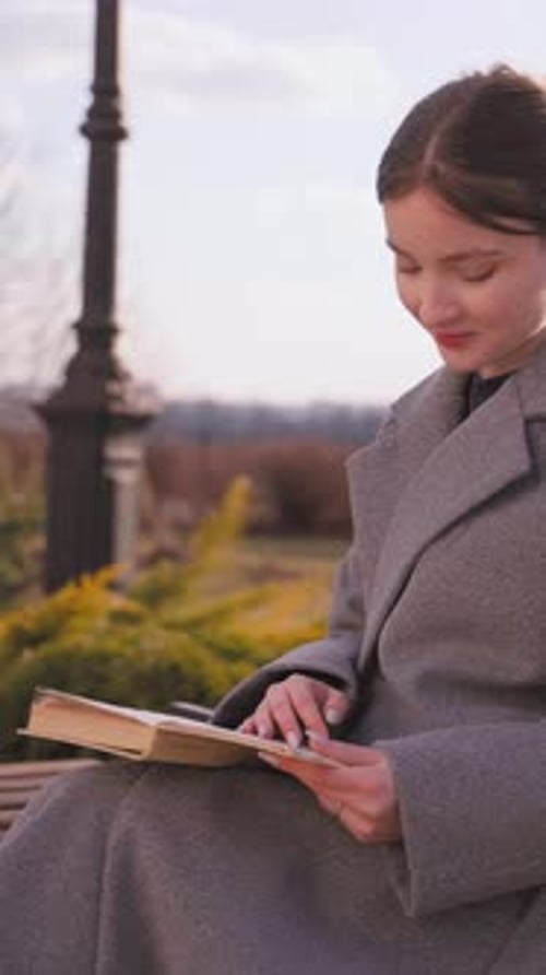 Young woman reading a book on a bench in a park