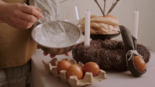 Lächelnde Frau in kuscheliger Hauskleidung, die sanft die Glasur für den Osterkuchen peitscht und den Zauber des Urlaubs genießt