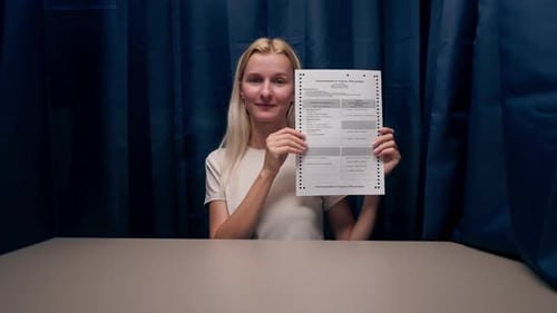 Closeup of a Young Girl in Wight Tshirt in a Booth Reading a Ballot with Presidential Candidates at