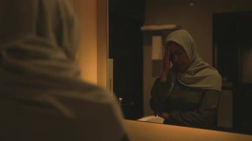 Woman with Hand on Forehead Reflected in Mirror