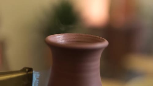 Close up rotating clay vase on pottery wheel glazed with propane torch flame