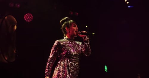 Woman Singing on Stage Under Stage Lights