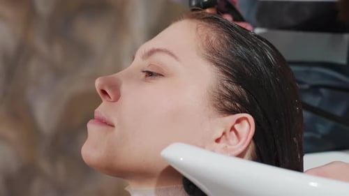 Woman Rinsing Hair in Salon Shampoo Bowl