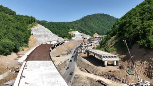 Aerial view of cranes and bridge foundation pillars on construction site of new highway road project