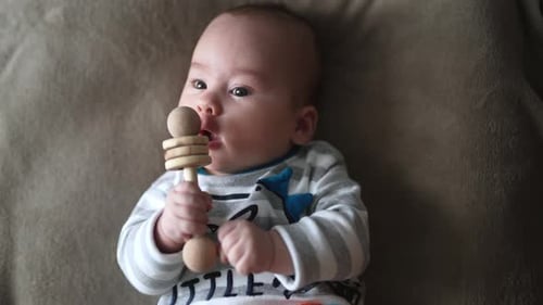Baby Lying Down Chewing on Wooden Toy
