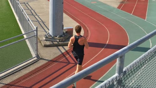 Young Adult Running on Track on a Sunny Day
