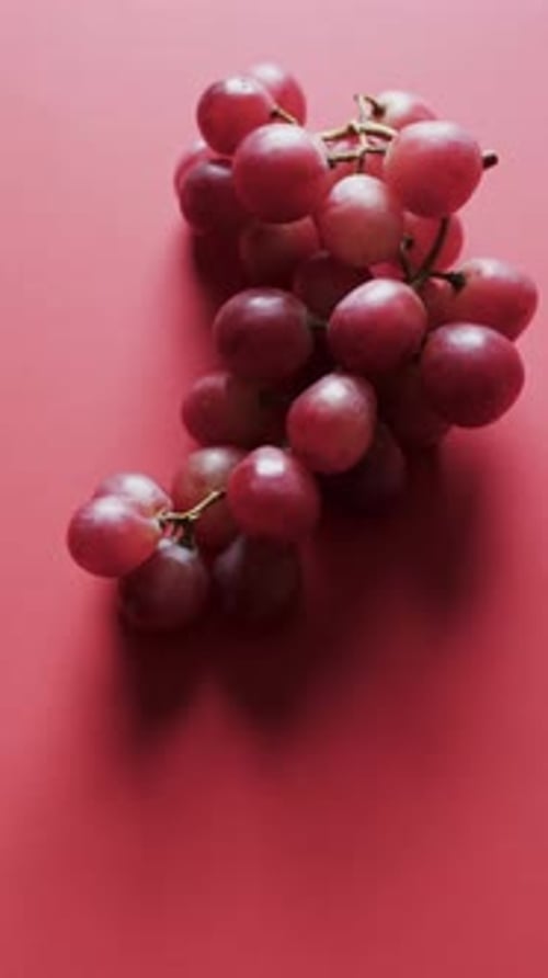 Vertical video of red grapes with copy space on red background