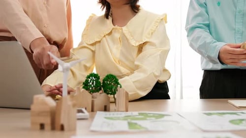 Business people consulting with house and windmill model on table. Delineation.