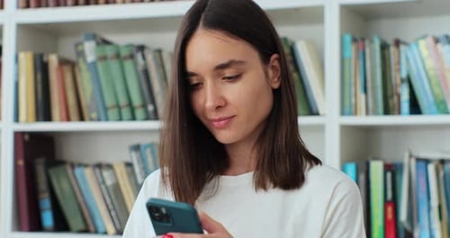 Close Up Student Girl Standing in Library and Using Smartphone Texting Message Check Online Studies