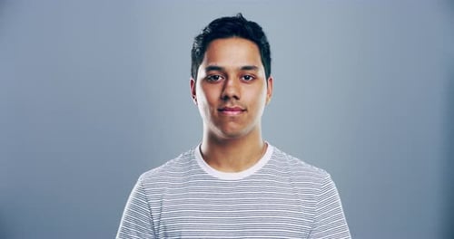 4K-Videomaterial eines jungen Mannes, der vor einem grauen Studiohintergrund lächelt