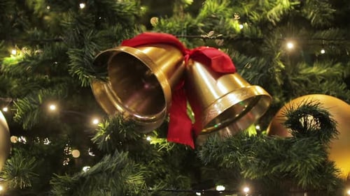 Christmas Bells on a Spruce Branch on the Background of New Year's Illumination