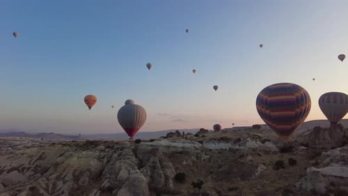 Hot Air Balloons Floating Over Rocky Landscape at Sunrise