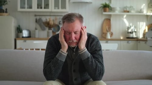 Man Sitting with Headache Pain at Home