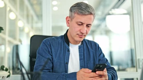Happy Business Man Smiling While Using Phone in Modern Office