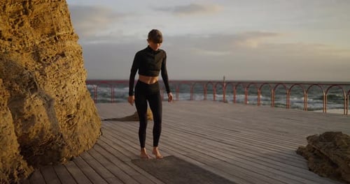 Woman Unrolls Yoga Mat for Beachside Workout