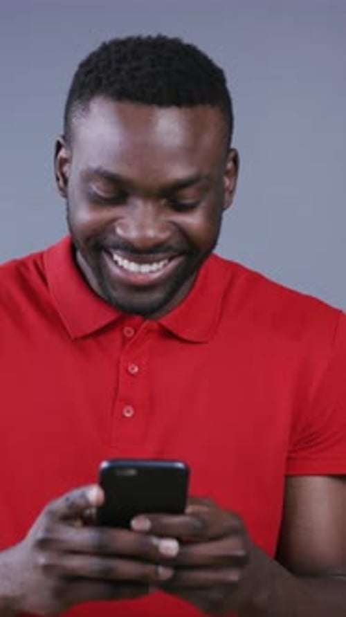 Smiling Man Uses Smartphone in Portrait Video