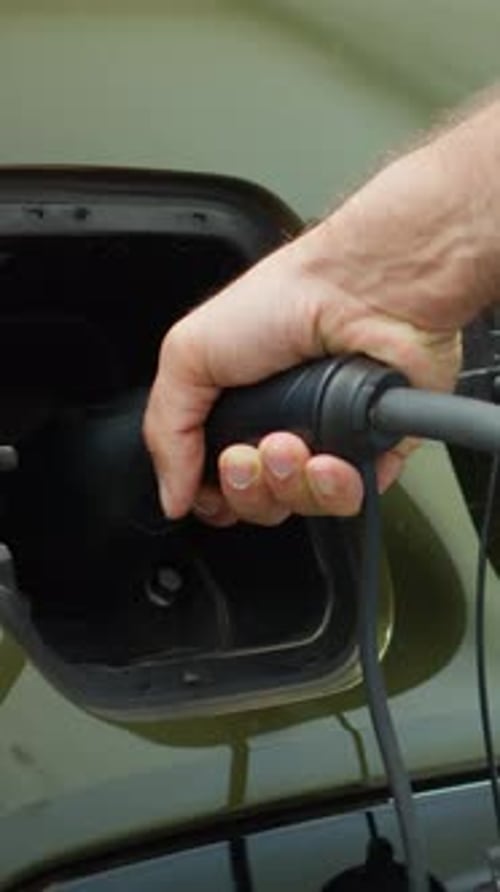 Vertical Video Close Up of Driver Attaching Electric Cable to EV Vehicle Charging Port