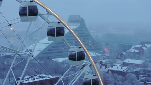 Ferris wheel and modern library building in a cold, misty city
