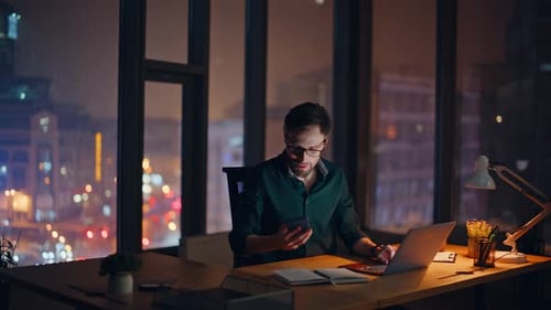 Business Analyst Speaking Cellphone Overtime at Dark Office Panoramic Window