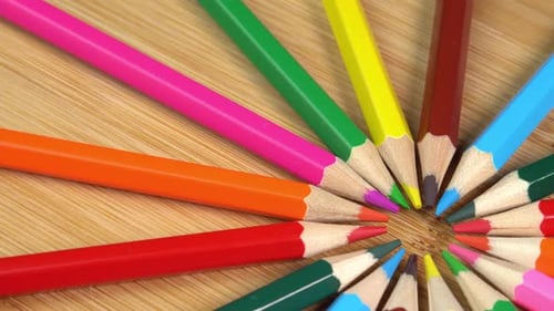 Colorful pencils rotate as sun rays background. Rainbow pencils for drawing. Assortment of colored