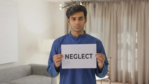 Sad Indian boy holding NEGLECT banner