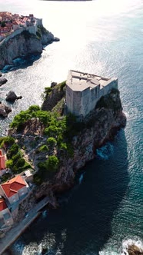 aerial portrait drone shot panning right of fort lovrjenac on Adriatic Sea cliffs coast in sunlight