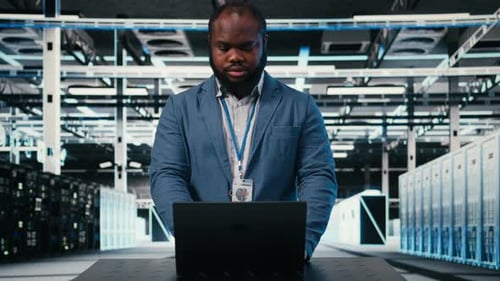 Man Working on Laptop in Data Server Room
