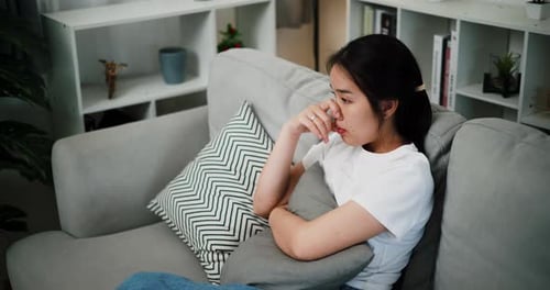 Woman with dark hair sitting on gray couch