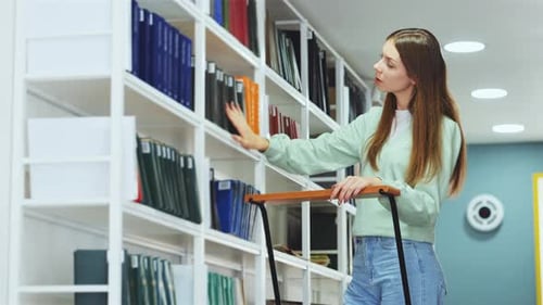 Un étudiant assidu sélectionne des livres sur une étagère de bibliothèque