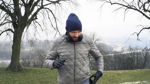 Sporty Man Setting Music on Smartphone in City Park 30s