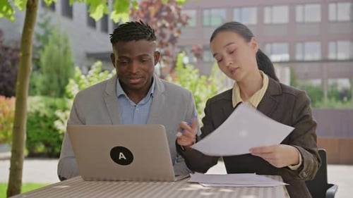 Two Professionals Reviewing Documents Outdoors in the City