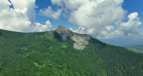 Flight over green mountain peaks. A beautiful sunny summer day at high altitude with thick clouds an