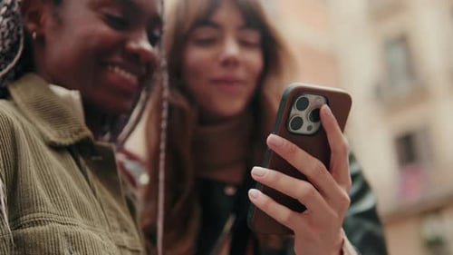Two Friends Enjoying Content on Smartphone Outdoors