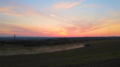 Tractor Spraying Fertilizers with Insecticide Herbicide Chemicals on Agricultural Field at Sunset
